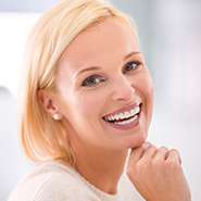 Blonde woman in white shirt looking back and smiling