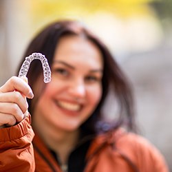 Woman smiling while holding clear aligner