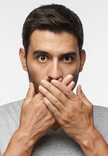 Bearded man covering his mouth with his hands