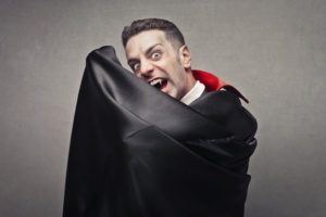 Man in a vampire costume posing and showing off pearly fangs